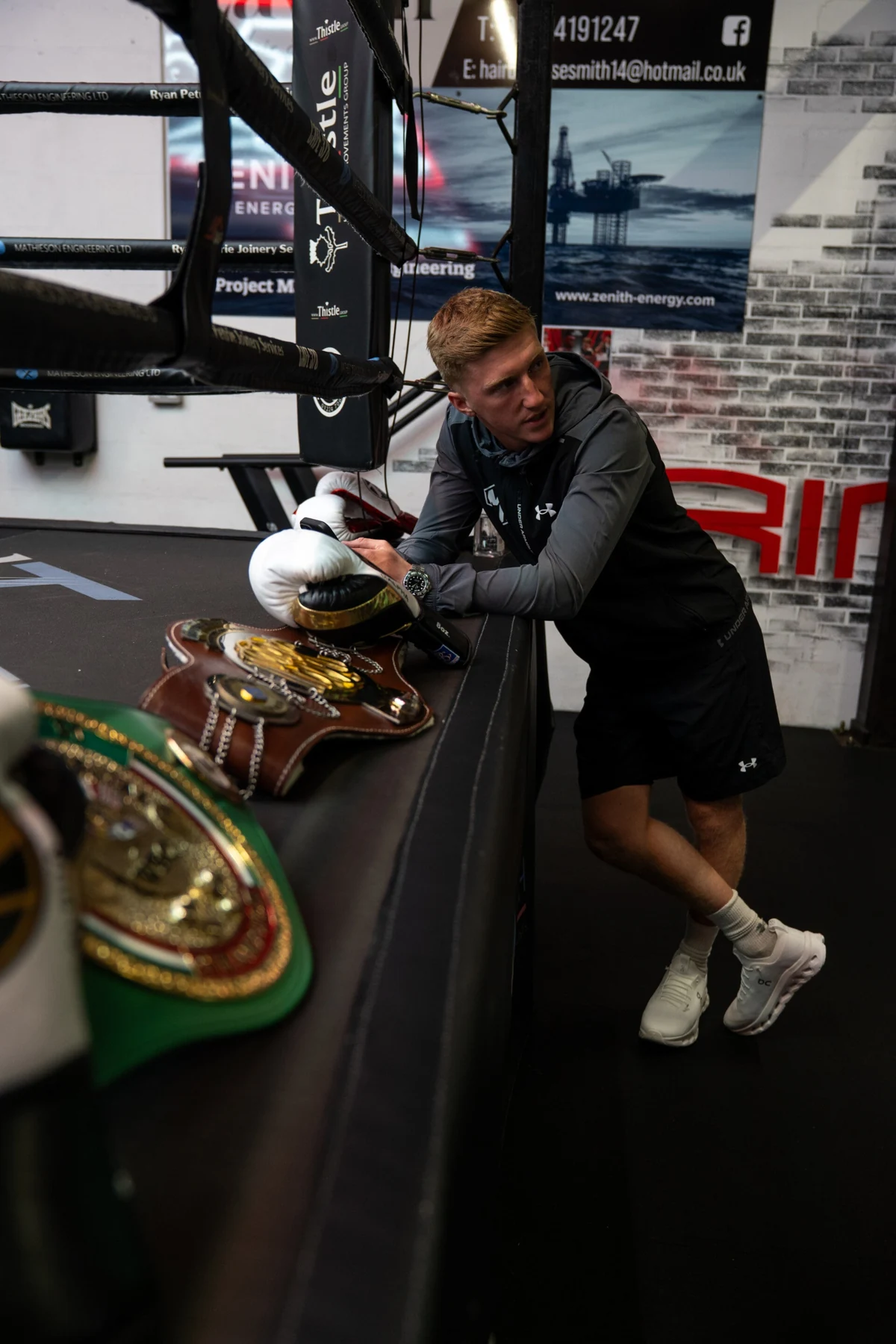 Gregor McPherson leans against the ring beside boxing gloves and belts at Bodbox Aberdeen